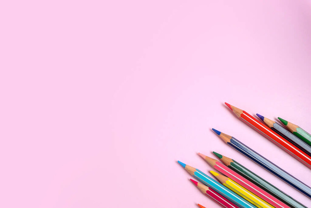 Color pencils on light pink background, top right view with space for text. Back to school concept. Flat lay stationary mockup. Bright colors - Photo, Image