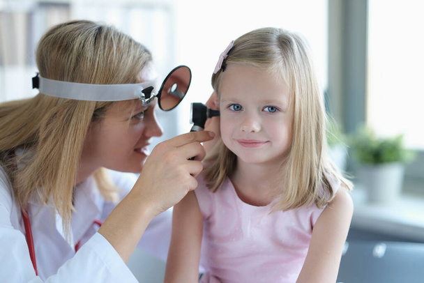 ΩΡΛ γιατρός εξετάζει τα μικρά κορίτσια αυτιά με ωτοσκόπιο closeup - Φωτογραφία, εικόνα