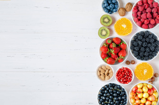 Fresh berries, fruits, nuts on a white wooden background. The concept of healthy eating. Food contains vitamins and trace elements. Copy space - Foto, imagen