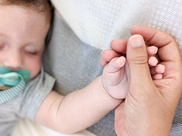 Peaceful sleeping baby holding his mother hand - Foto, imagen