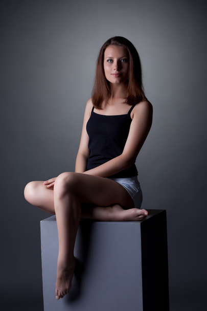Lovely slim woman posing sitting on cube - Фото, изображение