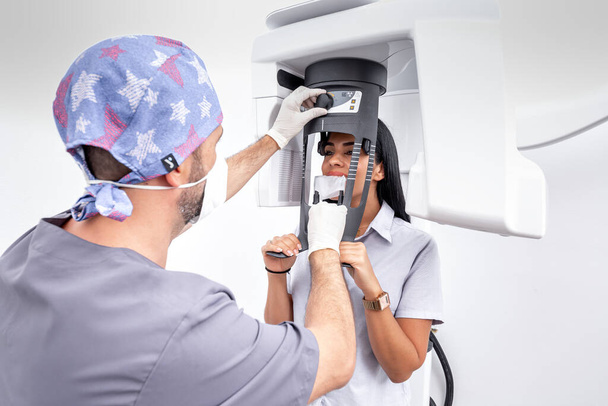 Odontólogo masculino ajustando una máquina de blanqueamiento dental usada por una paciente femenina en una clínica dental - Foto, Imagen