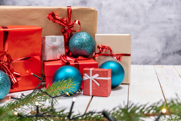 Χριστουγεννιάτικη σύνθεση διακοπών με κουτιά δώρων σε λευκό ξύλινο φόντο. Χριστουγεννιάτικα δώρα με κόκκινο, καφέ και γκρι χαρτί με κόκκινη κορδέλα, Χριστουγεννιάτικα στολίδια γύρω. - Φωτογραφία, εικόνα