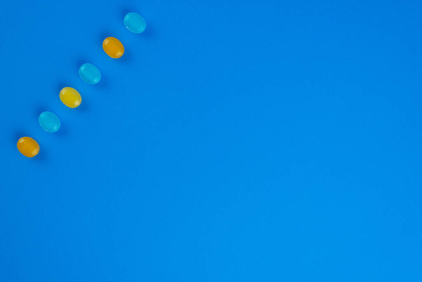 Montón de caramelos duros de colores colocados en la superficie azul.  - Foto, imagen