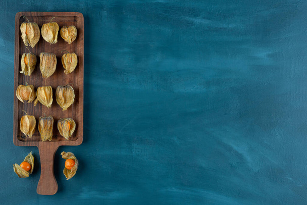 A wooden cutting board full of physalis berries   - Photo, Image