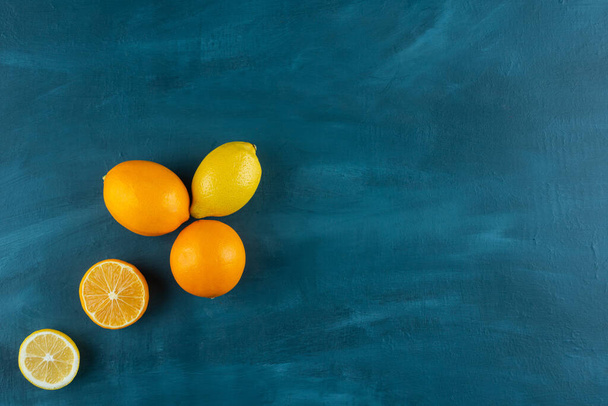 Frutos enteros y en rodajas de limón colocados sobre un fondo azul oscuro. Foto de alta calidad - Foto, imagen
