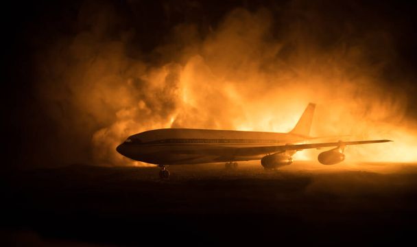 Flugzeugabsturz. Brennendes Flugzeug. Das Flugzeug stürzte zu Boden. Dekoriert mit Spielzeug auf dunklem Feuerhintergrund. Flugunfallkonzept. Selektiver Fokus - Foto, Bild