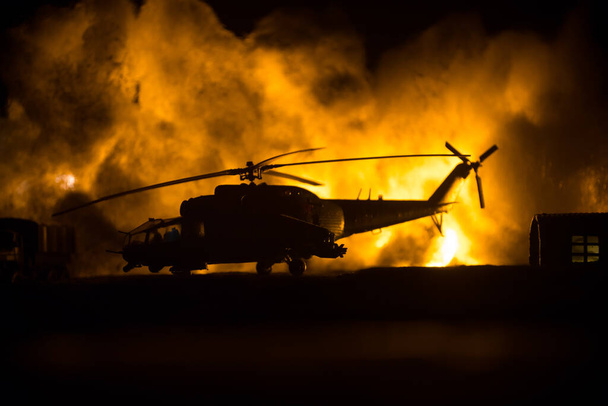 Silhouette of military helicopter ready to fly from conflict zone. Decorated night footage with helicopter starting in desert with foggy toned backlit. Selective focus. War concept - Fotó, kép