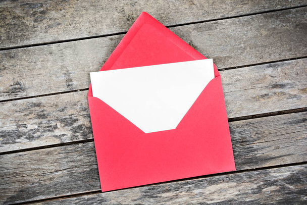 Prázdný bílý papír se umístí na otevřenou obálku z červeného papíru. Horní pohled - Fotografie, Obrázek