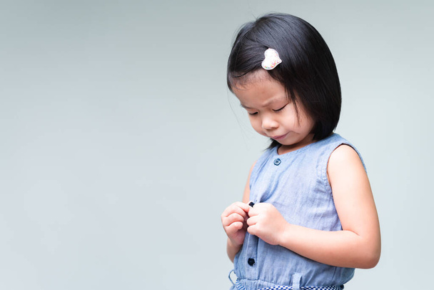 Portret Azjatki słodkie dziecko dziewczyna jest zapinanie jej koszulę. Koncepcja codziennej działalności, samopomocy. Przestrzeń kopiowania. - Zdjęcie, obraz