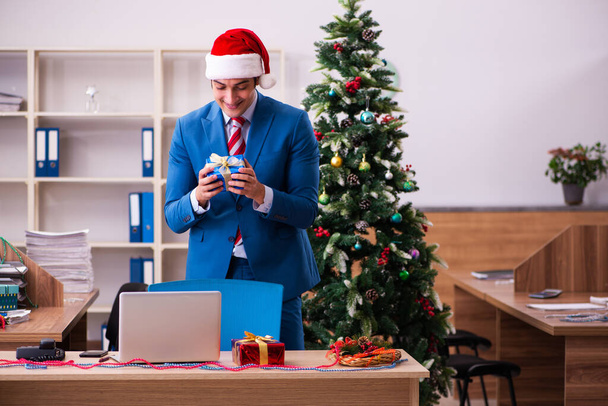 Nuori miespuolinen työntekijä viettää joulua työpaikalla - Valokuva, kuva