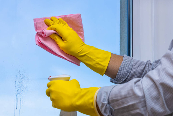moderne man helpt met huishoudelijke schoonmaak, raamreiniging, roze doek, kantoor shirt mouwen opgerold en venster schoner in de hand  - Foto, afbeelding