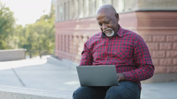 Feliz senior 60s envejecido cliente afroamericano utilizando ordenador portátil al aire libre de compras en línea. Anciano banco cliente hombre comprar bien en la tienda de Internet, satisfecho con los programas de servicio ok gesto recomienda aplicación - Metraje, vídeo
