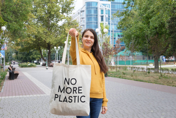 Eine Frau zeigt eine wiederverwendbare Stofftasche mit dem Text "Kein Plastik mehr" - Foto, Bild