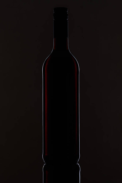 Plan vertical d'une bouteille de vin isolée sur fond noir - Photo, image