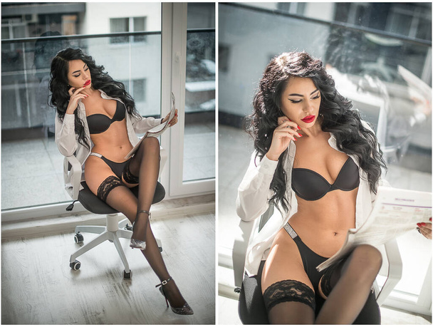 Attractive woman in black lingerie and long legs posing and reading the newspaper in front of a window. Classic boudoir scene. Indoor erotic photo. Sensual   woman with black stocking and high heels. - Zdjęcie, obraz