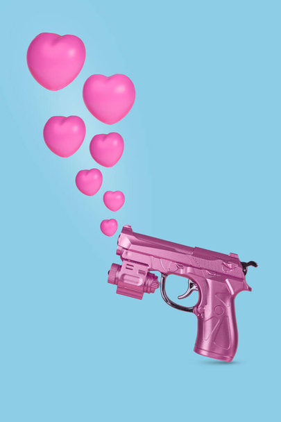 Креативные валентинки или романтическая концепция с розовым ружьем, стреляющим сердцами на голубом фоне. Минимальный уровень любви. - Фото, изображение