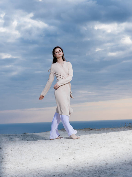 mooie vrouw in jas poseren strand frisse lucht elegante stijl - Foto, afbeelding