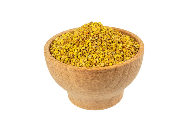 Bee pollen in wooden bowl isolated on white background. Natural herbal medicine to relieve inflammation, influenza, boosts liver health, strengthens immune system, reduces stress and used as a dietary supplement. - Photo, Image