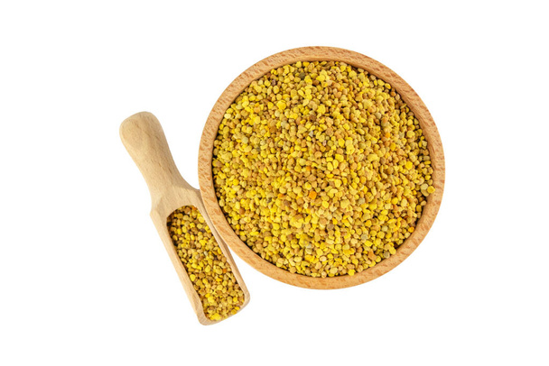 Bee pollen in wooden bowl and scoop isolated on white background. Natural herbal medicine to relieve inflammation, influenza, boosts liver health, strengthens immune system, reduces stress and used as a dietary supplement. - Photo, Image