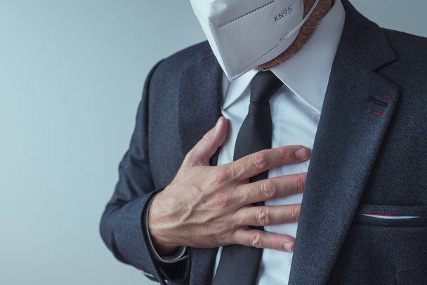 Eleganter Geschäftsmann mit Atemschutzmaske KN95 mit starken Schmerzen in der Brust, selektiver Fokus - Foto, Bild