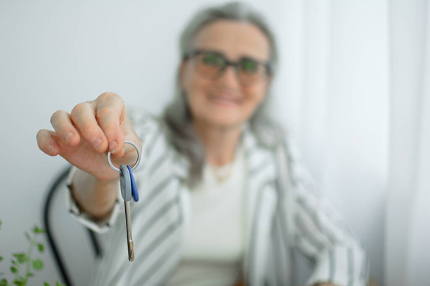 Senior realtor, estate agent makes real estate deal with home buyers, gives the keys frome new house with smile, mortgage loan, leasing service, sale purchase contract concepts - 写真・画像