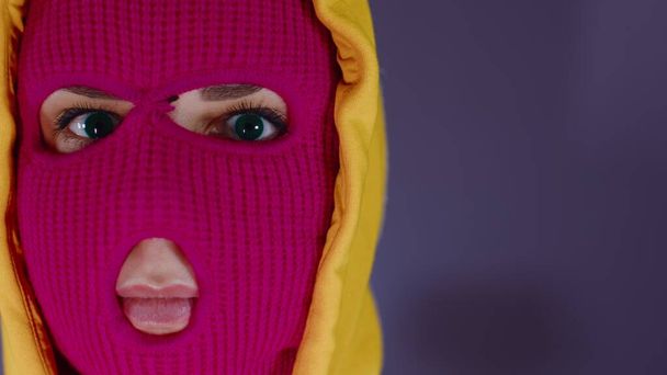 Portrait of young woman in pink balaclava. Close up of hooligan in mask. - Foto, imagen