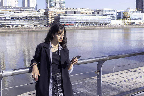Jovem mulher no porto usando celular em um dia ensolarado - Foto, Imagem