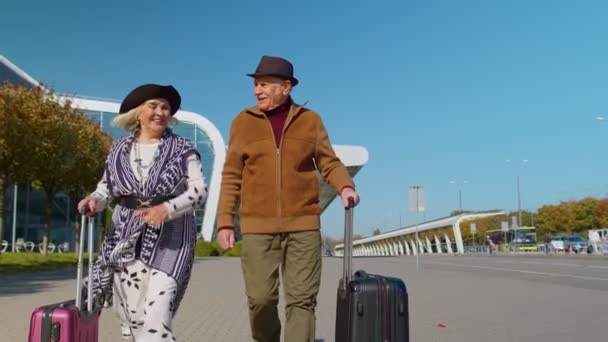 Iäkäs aviomies vaimo eläkeläiset turistit mennä lentokentälle terminaalin lennolle matkatavarat pyörillä - Materiaali, video