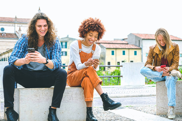 Multikulturní skupina přátel pomocí mobilních telefonů - Studenti sedí v řadě a píší na chytrých telefonech - Fotografie, Obrázek
