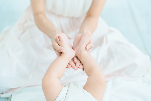 Le mani della mamma sostengono i piedi del bambino nella stanza - Foto, immagini