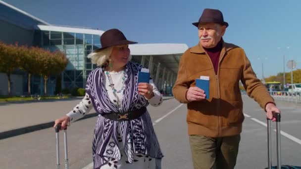 Manžel manželka důchodci turisté jdou na letiště terminál pro stravování se zavazadly, jízdenky, pasy - Záběry, video