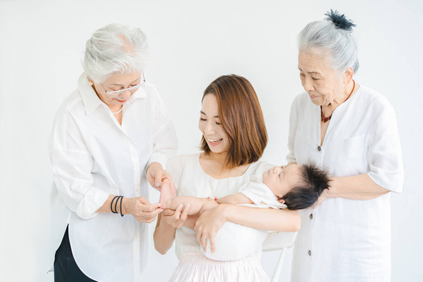 Азійська мама тримає дитину і двох старших жінок. - Фото, зображення