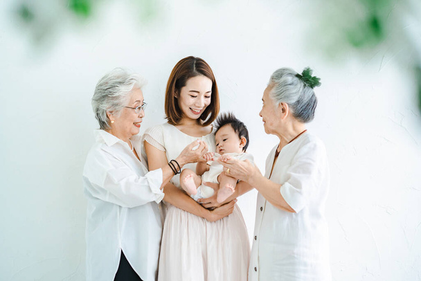 Ασιάτισσα μητέρα που κρατάει ένα μωρό και δύο ηλικιωμένες γυναίκες - Φωτογραφία, εικόνα