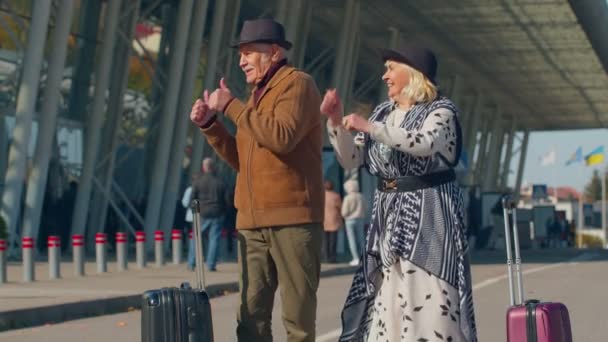 Idős férj feleség nyugdíjasok turisták megy a repülőtér terminál beszállás poggyász kerekeken - Felvétel, videó