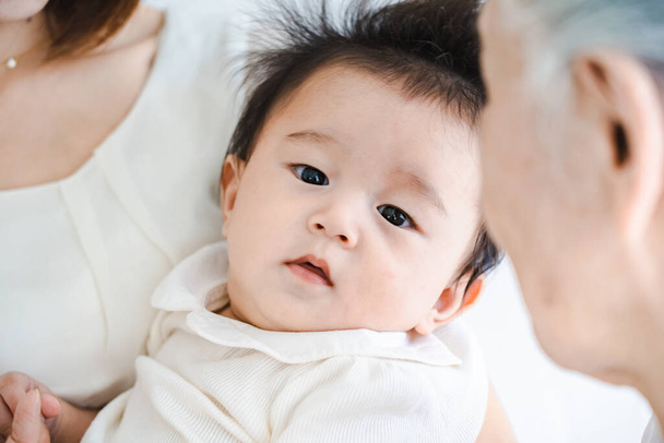 Asiatisches Baby wird in einem hellen Raum umarmt - Foto, Bild