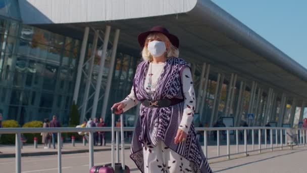 Yaşlı turist büyükannesi Koruyucu Yüz Maskesi takıyor. Havaalanı yakınlarında koronavirüsten kaçının. - Video, Çekim