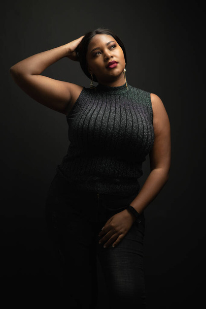 Portrait of black woman plus size posing and smiling with confident while looking toward to camera in the dark background. - Foto, imagen