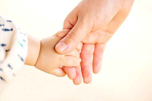 Family scene , closeup parent and baby holding hands together outdoors on white background. - Foto, Bild