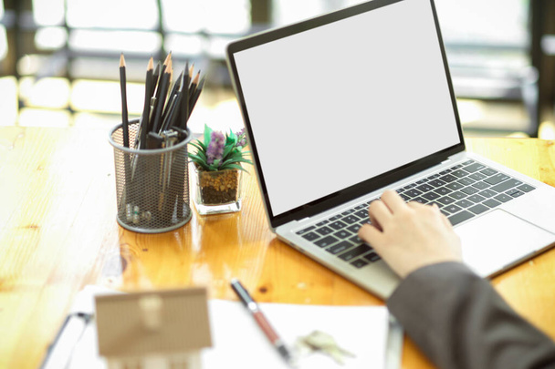Oříznutý obrázek pracoviště s otevřeným laptopem prázdná obrazovka maketa pro montáž a ženskou rukou psaní na klávesnici. - Fotografie, Obrázek