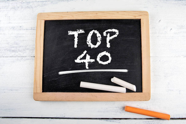 Top 40. Zwart krijtbord met krijtstukken op een witte tafel - Foto, afbeelding
