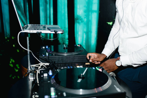 Sluit de DJ-console op het feest. Neon licht over de handen van het spelen op de bruiloft. - Foto, afbeelding