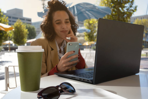 Латиноамериканка улыбается, делая перерыв во время работы, фокусируясь на кофе и солнцезащитных очках с пространством для копирования - Фото, изображение