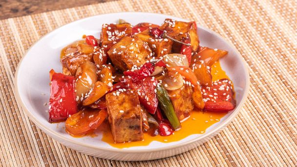 Sekoita paistettua tofua sipulin ja pippurin kanssa tulisessa kastikkeessa lautasella - aasialainen kasvisruoka - Valokuva, kuva