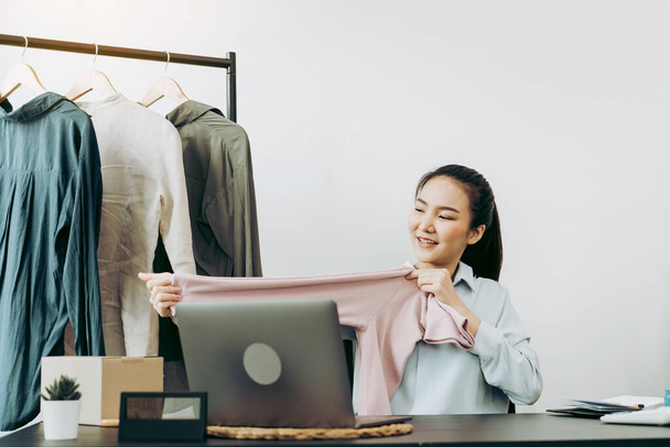 Młodzi azjatyccy przedsiębiorcy zbierają koszulki, aby porównać proporcje klientów do oglądania ich online. - Zdjęcie, obraz