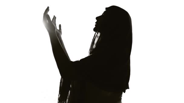 silhouet van een vrouw die voor het licht bidt - Video
