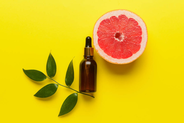 Fles grapefruit essentiële olie op kleur achtergrond - Foto, afbeelding