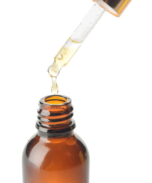 Gocciolamento di olio essenziale dalla pipetta in bottiglia su fondo bianco - Foto, immagini