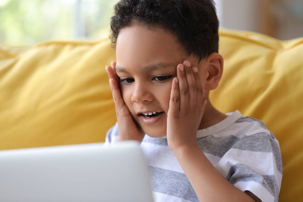 Surprised little African-American boy with laptop watching cartoons at home, closeup - Photo, Image