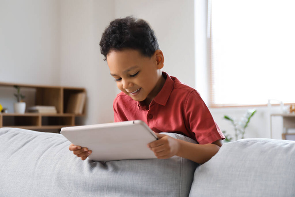 Kleiner afroamerikanischer Junge schaut Cartoons auf Tablet-Computer zu Hause - Foto, Bild